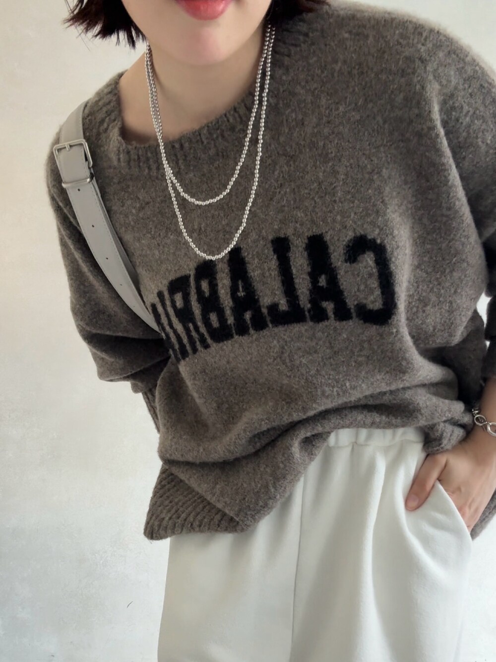 ベージュ系のニット/セーター、ホワイト系のスウェットパンツ、グレー系のショルダーバッグを着用したレディースの秋コーディネートの5枚目の写真