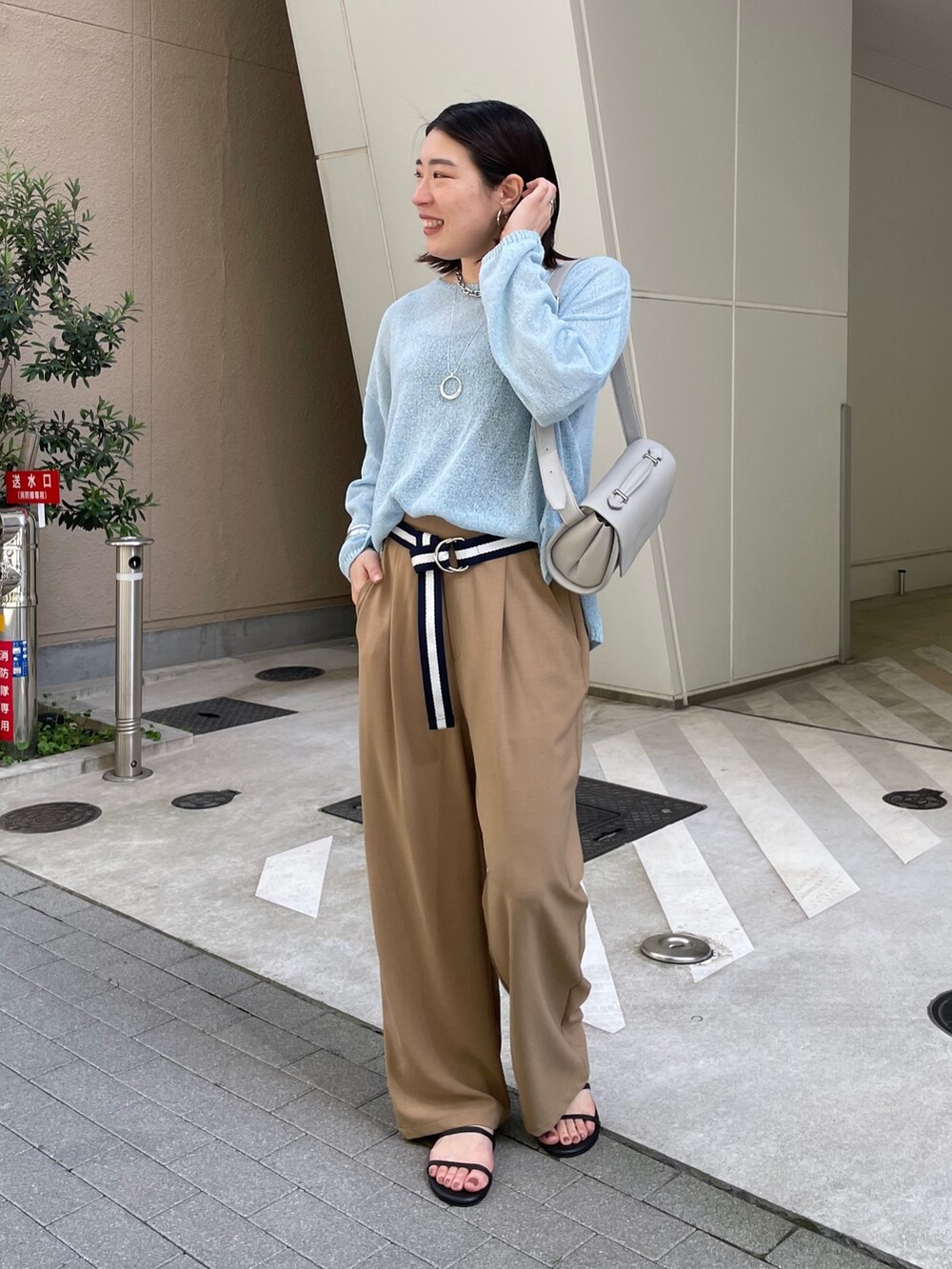 グレー系のスラックス、ブルー系のニット/セーター、ブルー系のベルトを着用したレディースの春コーディネートの3枚目の写真