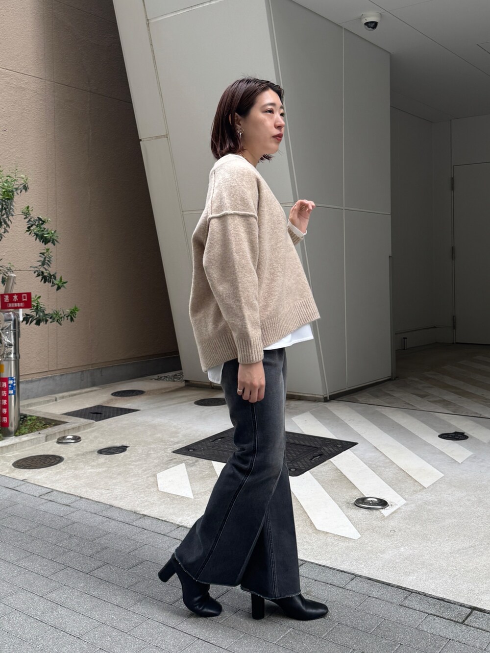 ブラック系のデニムパンツ、ベージュ系のニット/セーター、ホワイト系のTシャツ/カットソーを着用したレディースの秋コーディネートの5枚目の写真