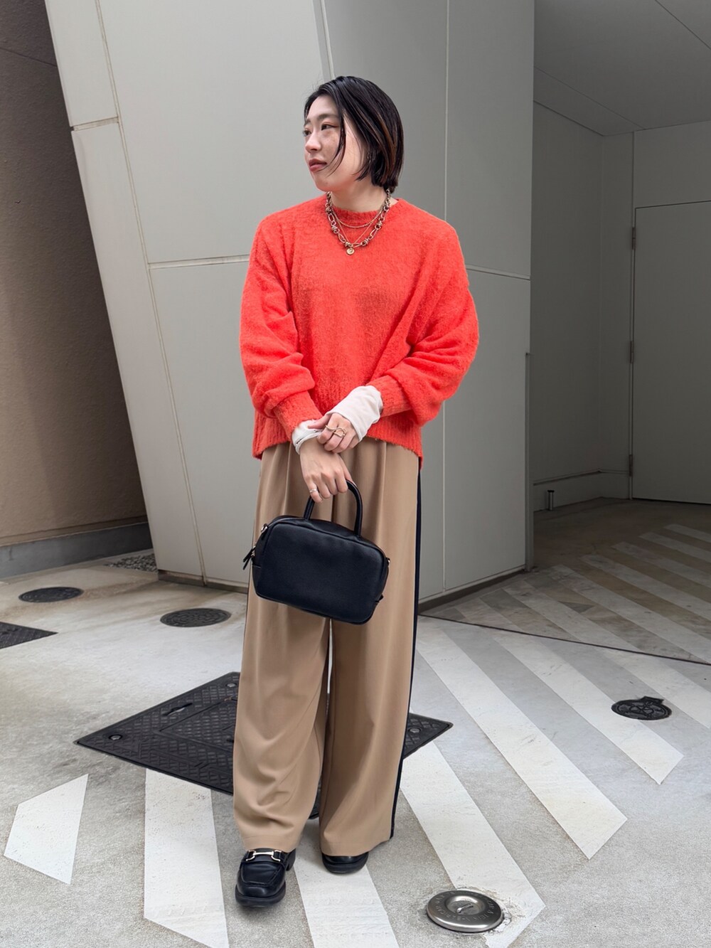 ベージュ系のその他パンツ、ホワイト系のその他アウター、オレンジ系のニット/セーターを着用したレディースの冬コーディネートの4枚目の写真