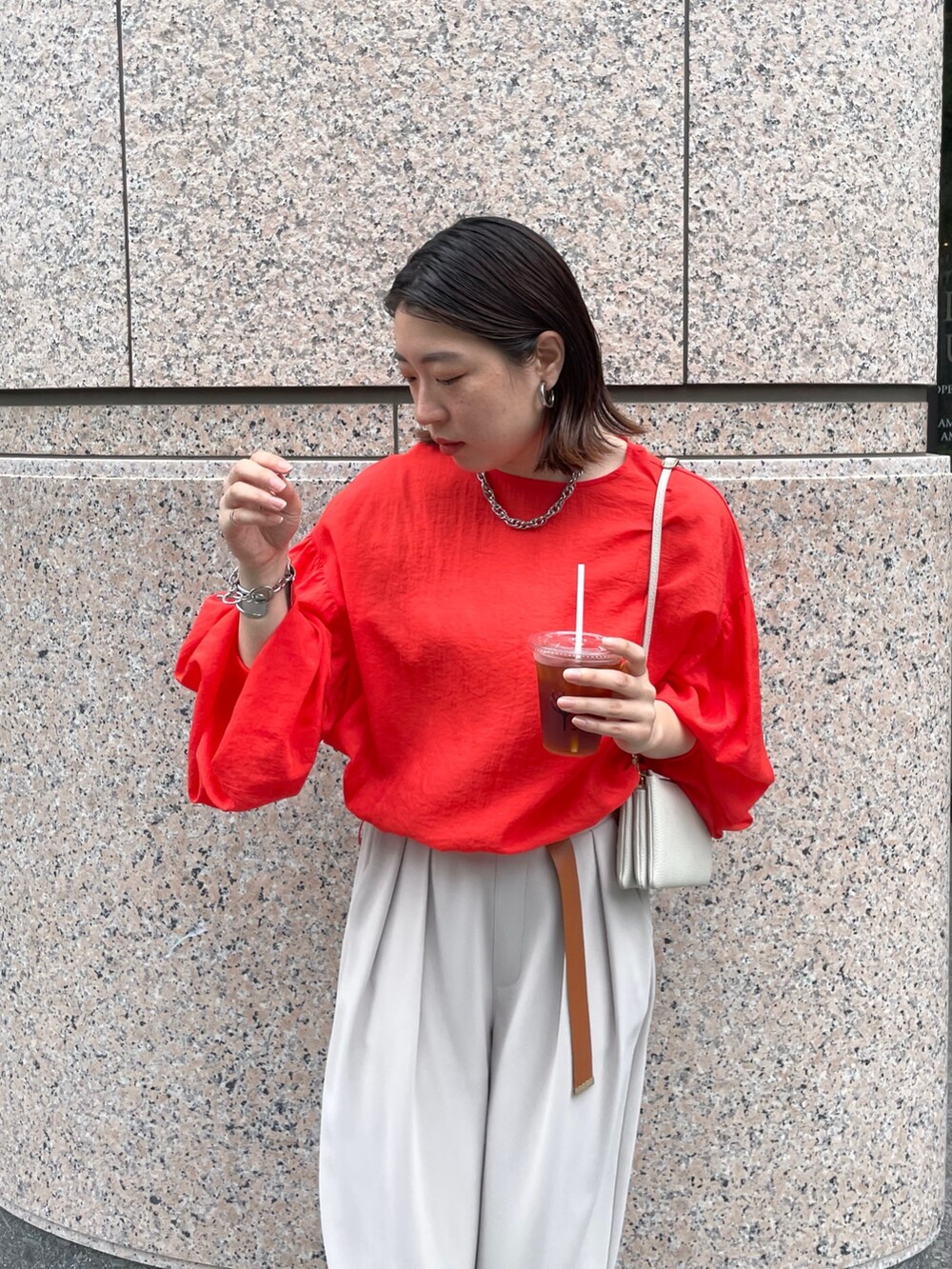 グレー系のスラックス、オレンジ系のシャツ/ブラウス、ホワイト系のショルダーバッグを着用したレディースの春コーディネートの8枚目の写真