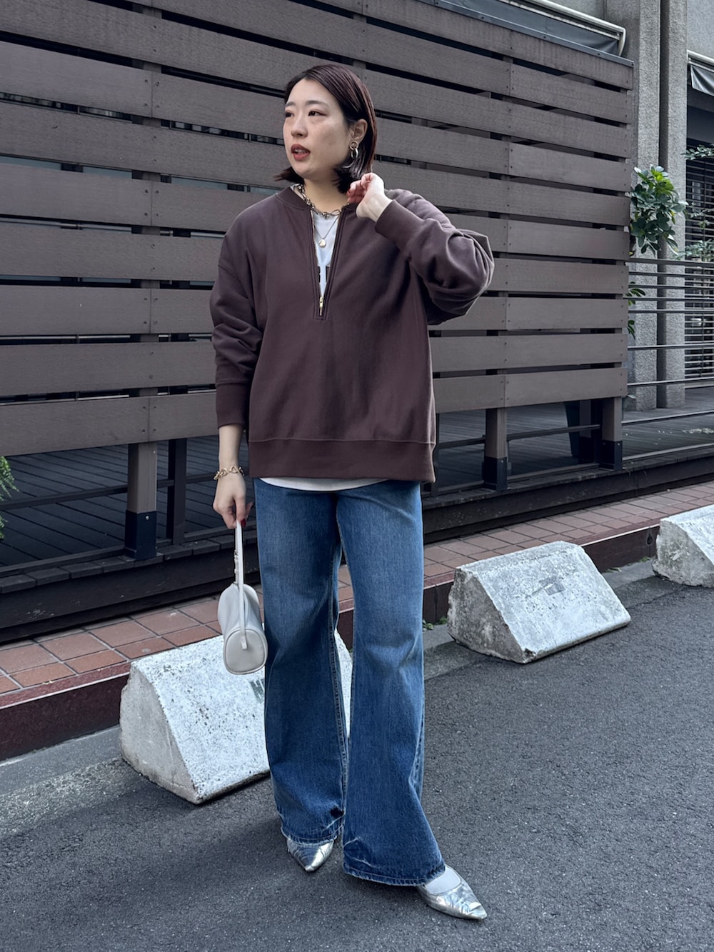 ブラウン系のスウェット、グレー系のシャツ/ブラウス、ブルー系のデニムパンツを着用したレディースの冬コーディネートの2枚目の写真