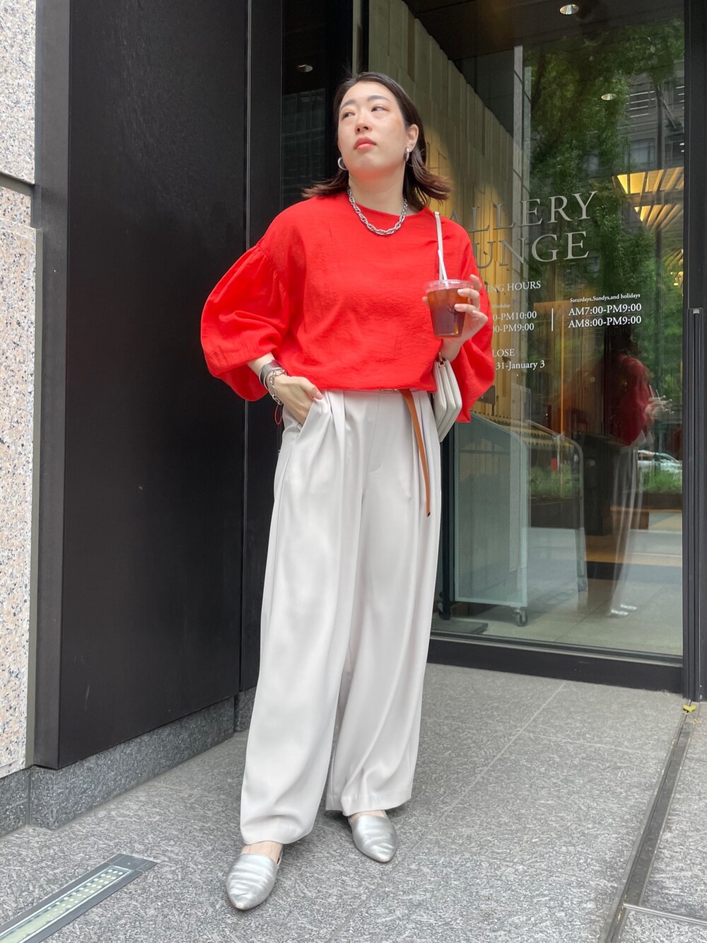 グレー系のスラックス、オレンジ系のシャツ/ブラウス、ホワイト系のショルダーバッグを着用したレディースの春コーディネートの6枚目の写真