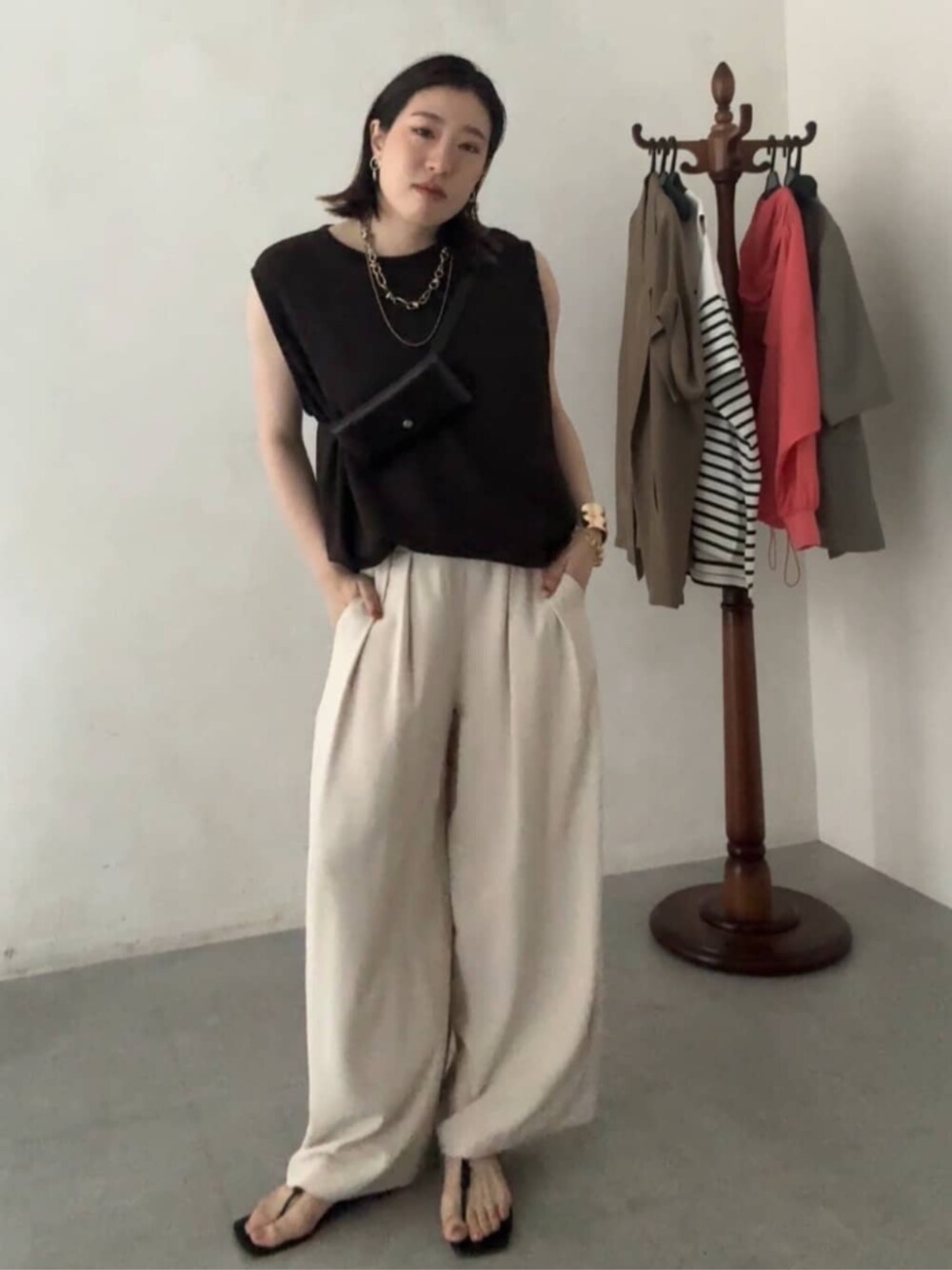 ブラウン系のショルダーバッグ、ブラウン系のTシャツ/カットソー、ベージュ系のスラックスを着用したレディースの夏コーディネートの4枚目の写真