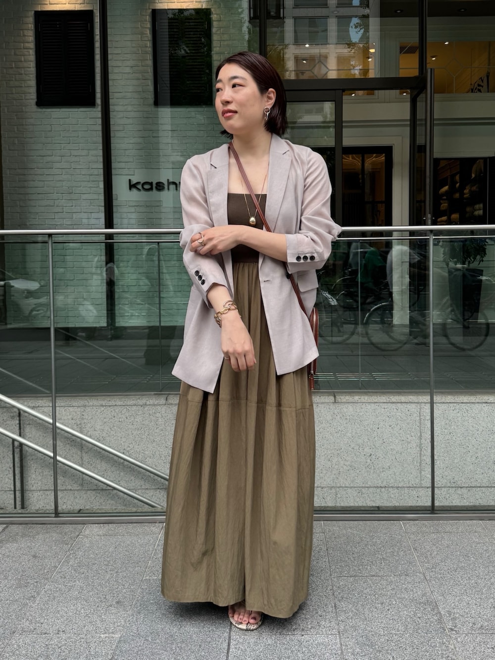 グリーン系のワンピース、ベージュ系のテーラードジャケット、ゴールド系のネックレスを着用したレディースの夏コーディネートの4枚目の写真