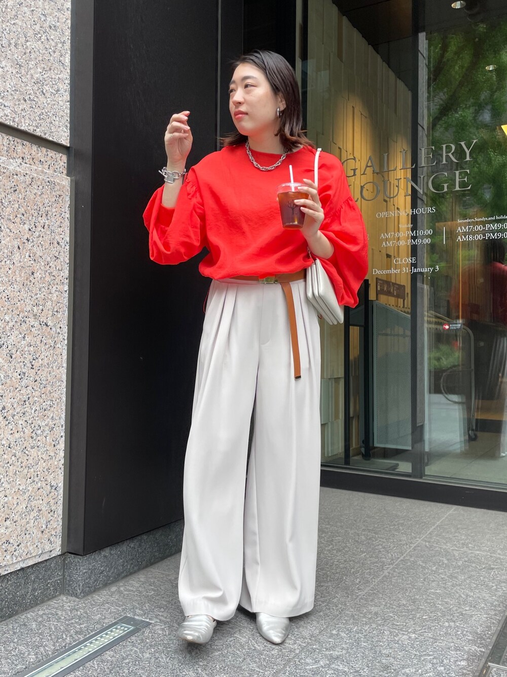 グレー系のスラックス、オレンジ系のシャツ/ブラウス、ホワイト系のショルダーバッグを着用したレディースの春コーディネートの4枚目の写真