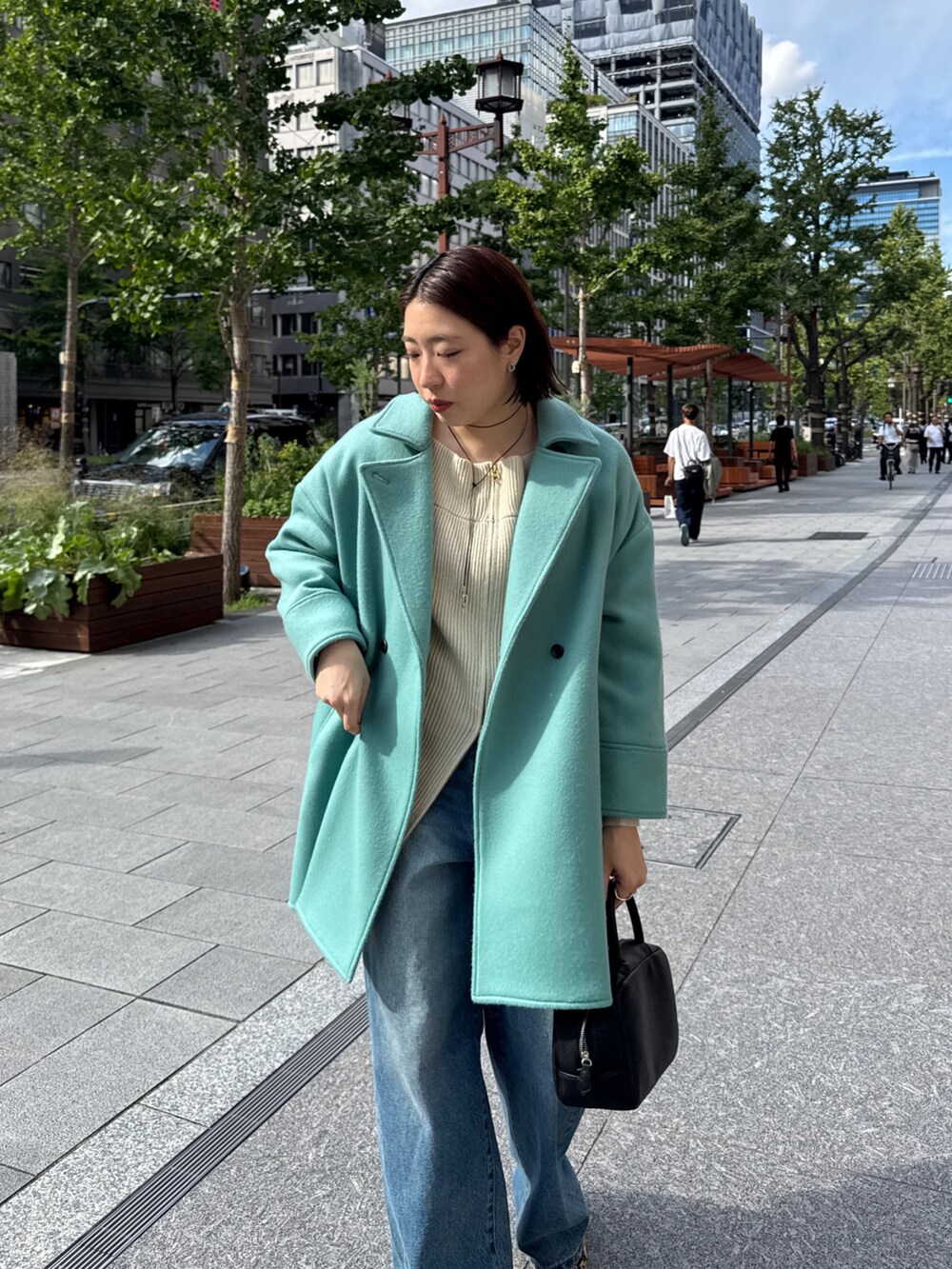 ベージュ系のニット/セーター、グリーン系のその他アウター、ブルー系のデニムパンツを着用したレディースの秋コーディネートの6枚目の写真