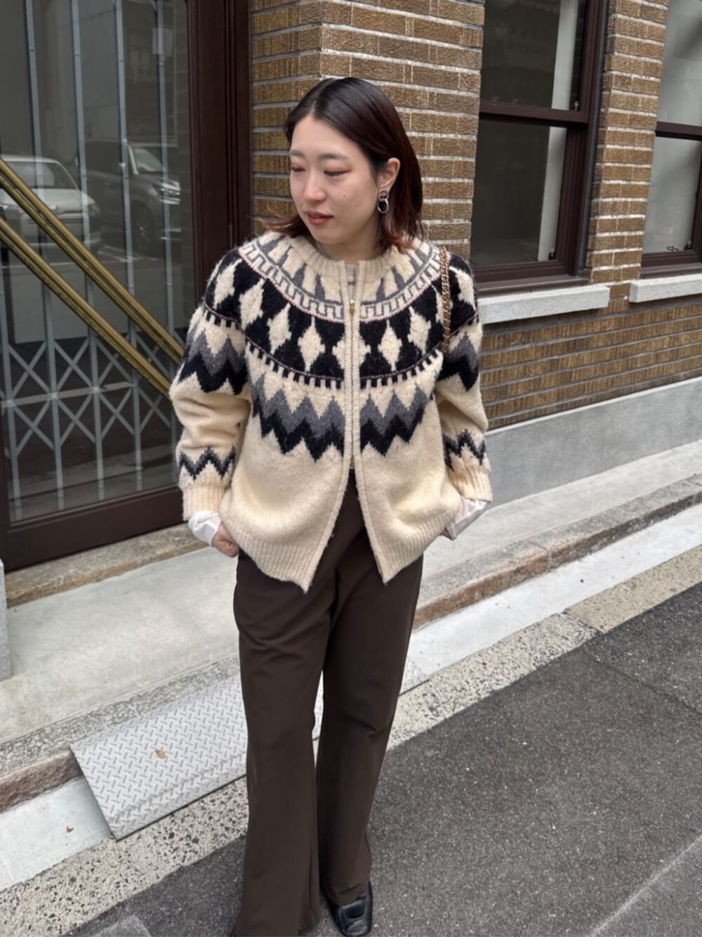 イエロー系のショルダーバッグ、ホワイト系のカーディガン/ボレロ、ブラウン系のその他パンツを着用したレディースの冬コーディネートの9枚目の写真