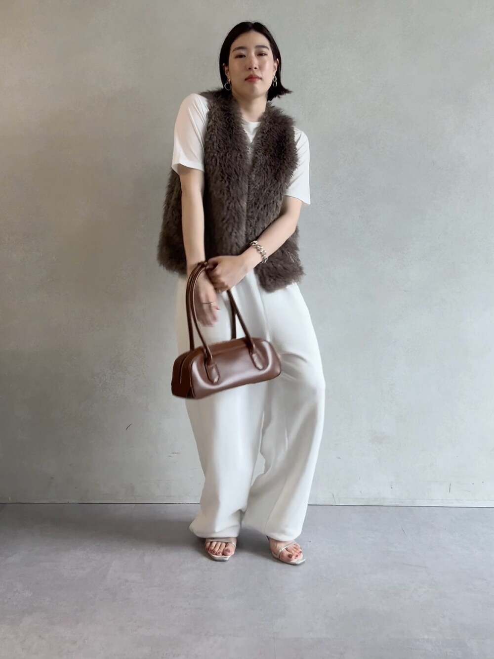 ホワイト系のスウェットパンツ、グレー系のベスト、ブラウン系のショルダーバッグを着用したレディースの秋コーディネートの4枚目の写真