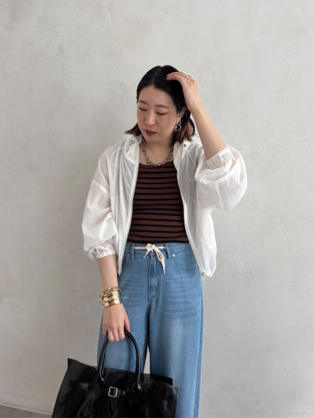 ブラック系のショルダーバッグ、ブルー系のデニムパンツ、ブラウン系のニット/セーターを着用したレディースの夏コーディネートの6枚目の写真