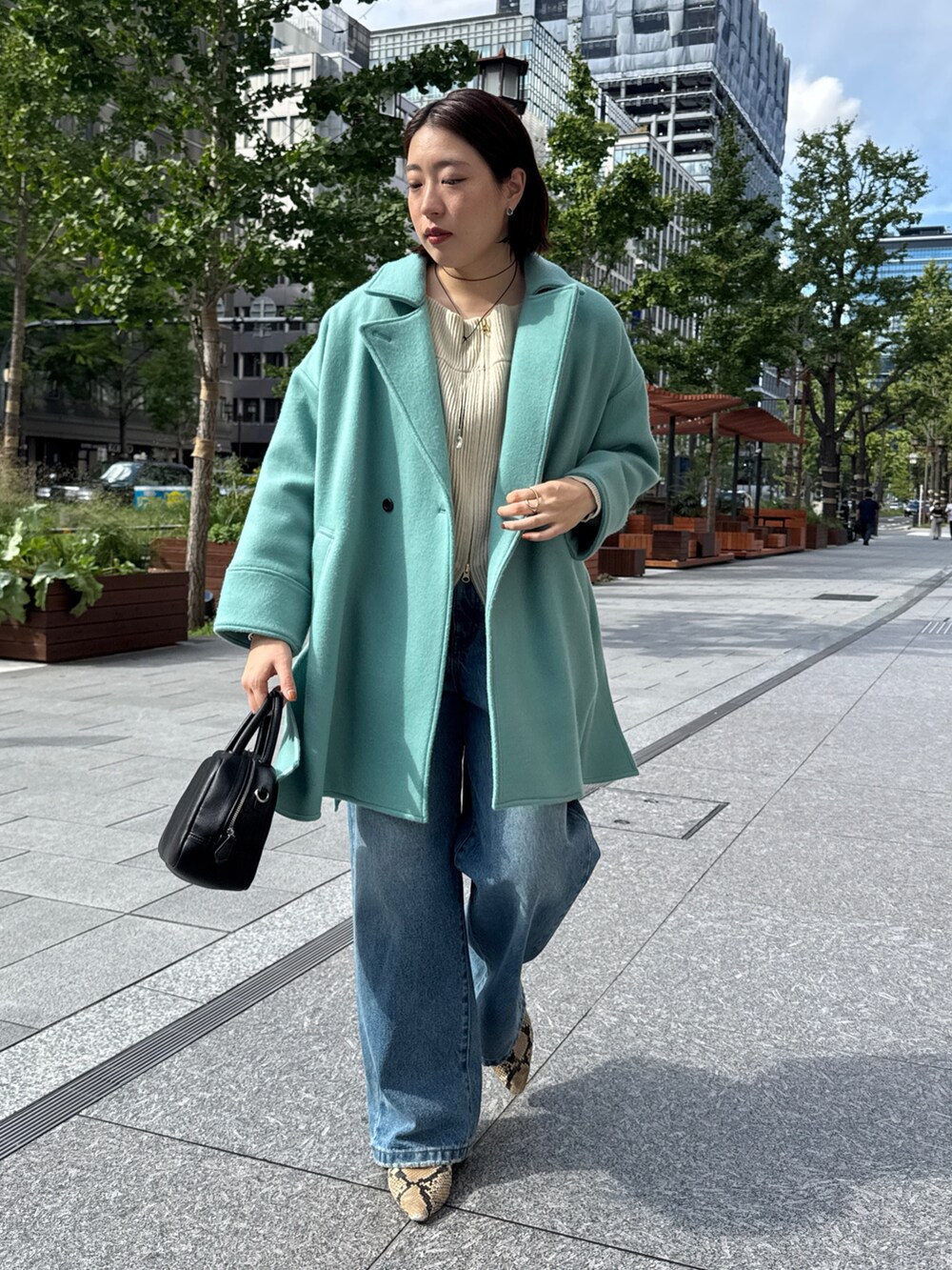 ベージュ系のニット/セーター、グリーン系のその他アウター、ブルー系のデニムパンツを着用したレディースの秋コーディネートの3枚目の写真