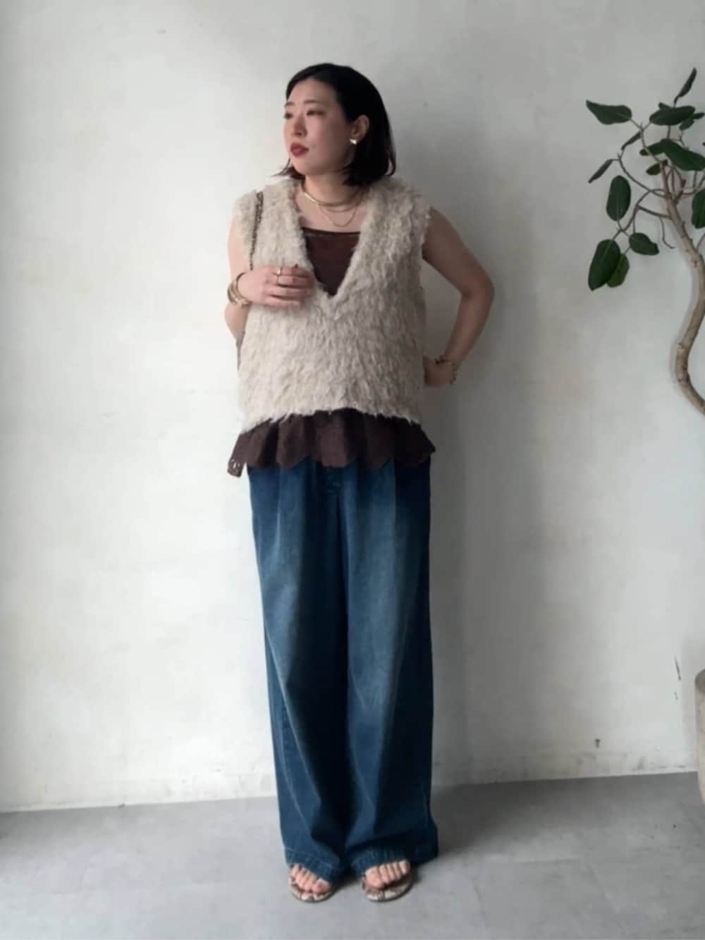 グレー系のショルダーバッグ、ベージュ系のニット/セーター、ブルー系のデニムパンツを着用したレディースの秋コーディネートの3枚目の写真