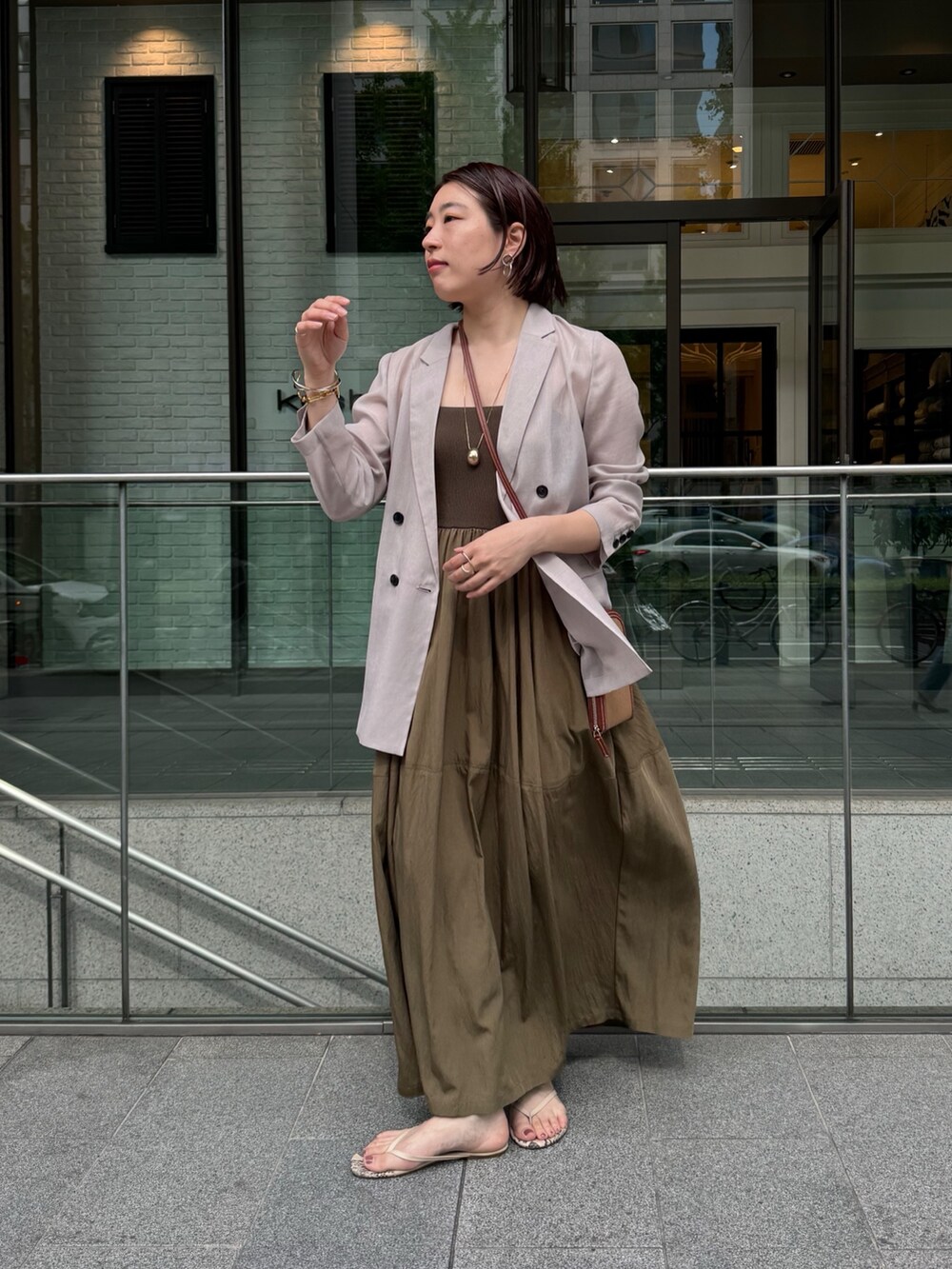 グリーン系のワンピース、ベージュ系のテーラードジャケット、ゴールド系のネックレスを着用したレディースの夏コーディネートの3枚目の写真