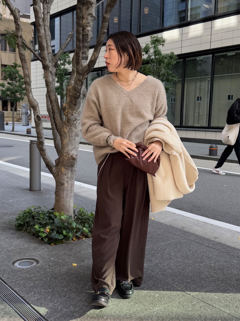 ブラウン系のスラックス、ブラウン系のニット/セーター、ホワイト系のその他アウターを着用したレディースの冬コーディネートの6枚目の写真