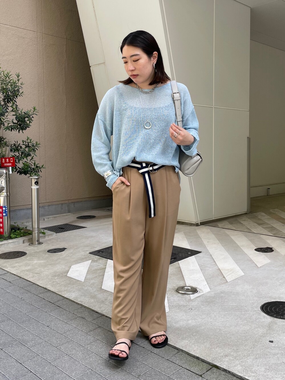 グレー系のスラックス、ブルー系のニット/セーター、ブルー系のベルトを着用したレディースの春コーディネートの4枚目の写真