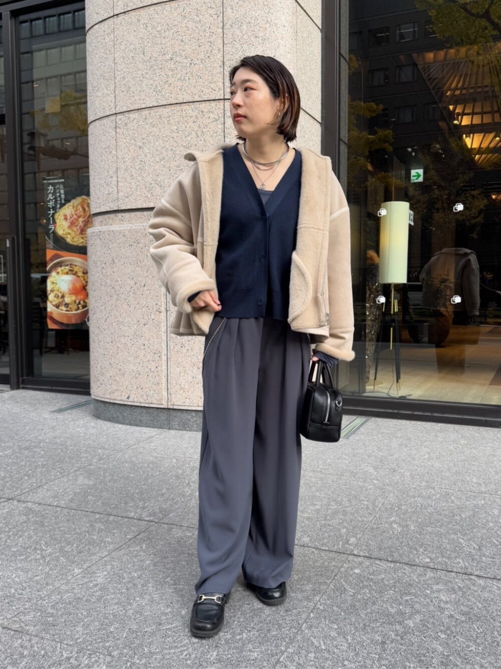 グレー系のスラックス、ブラック系のショルダーバッグ、ベージュ系のその他アウターを着用したレディースの冬コーディネートの5枚目の写真