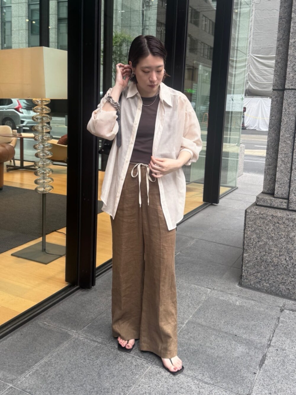 ブラウン系のショルダーバッグ、ブラウン系のTシャツ/カットソー、ベージュ系のシャツ/ブラウスを着用したレディースの夏コーディネートの2枚目の写真