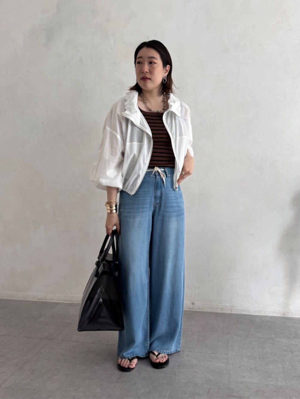 ブラック系のショルダーバッグ、ブルー系のデニムパンツ、ブラウン系のニット/セーターを着用したレディースの夏コーディネートの7枚目の写真