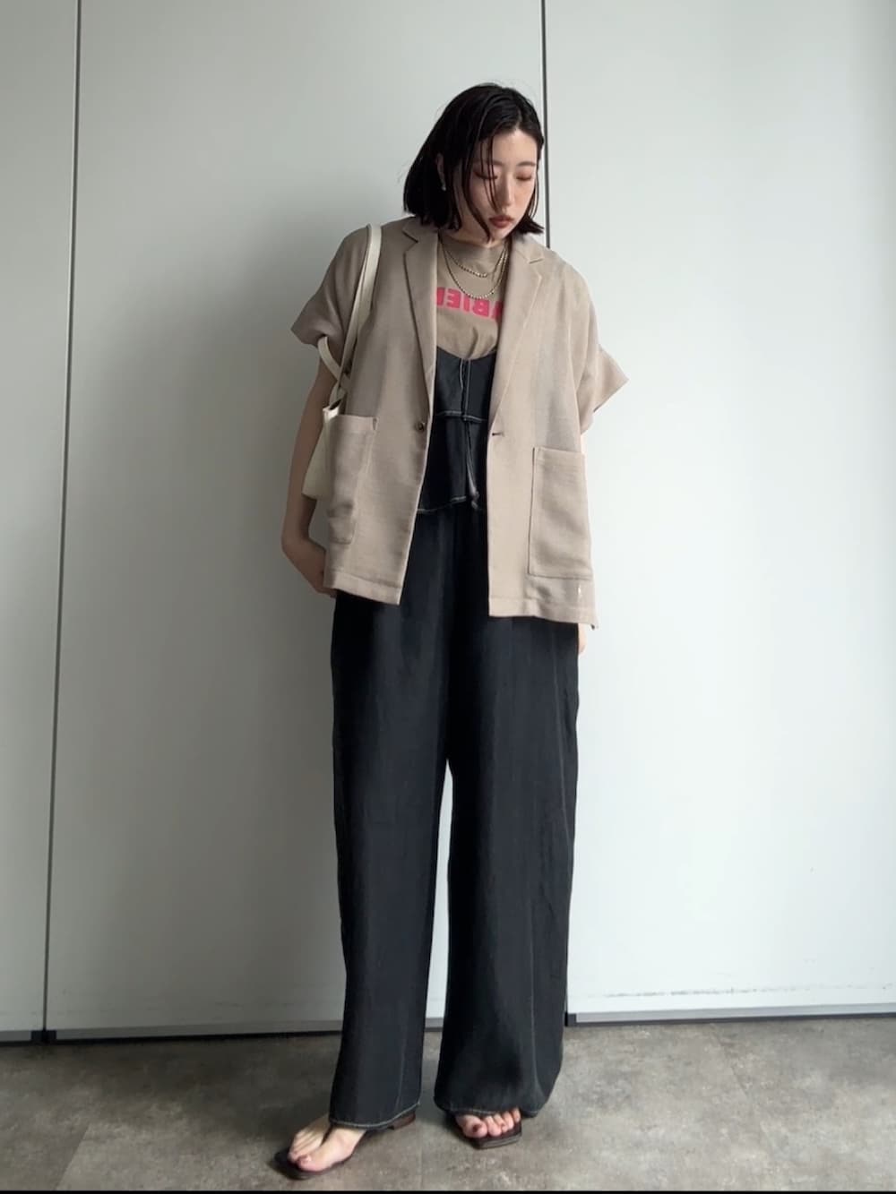 ベージュ系のテーラードジャケット、ベージュ系のTシャツ/カットソー、ブラック系のつなぎ/オールインワンを着用したレディースの夏コーディネートの4枚目の写真