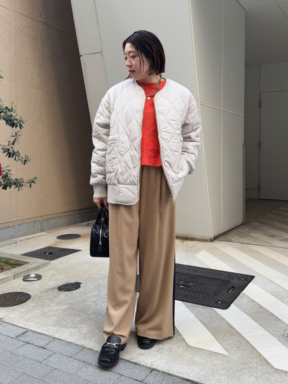 ベージュ系のその他パンツ、ホワイト系のその他アウター、オレンジ系のニット/セーターを着用したレディースの冬コーディネートの2枚目の写真