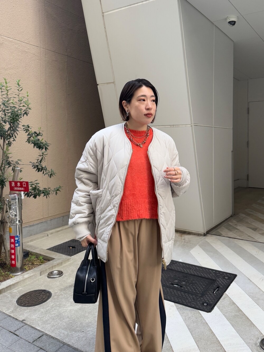 ベージュ系のその他パンツ、ホワイト系のその他アウター、オレンジ系のニット/セーターを着用したレディースの冬コーディネートの9枚目の写真