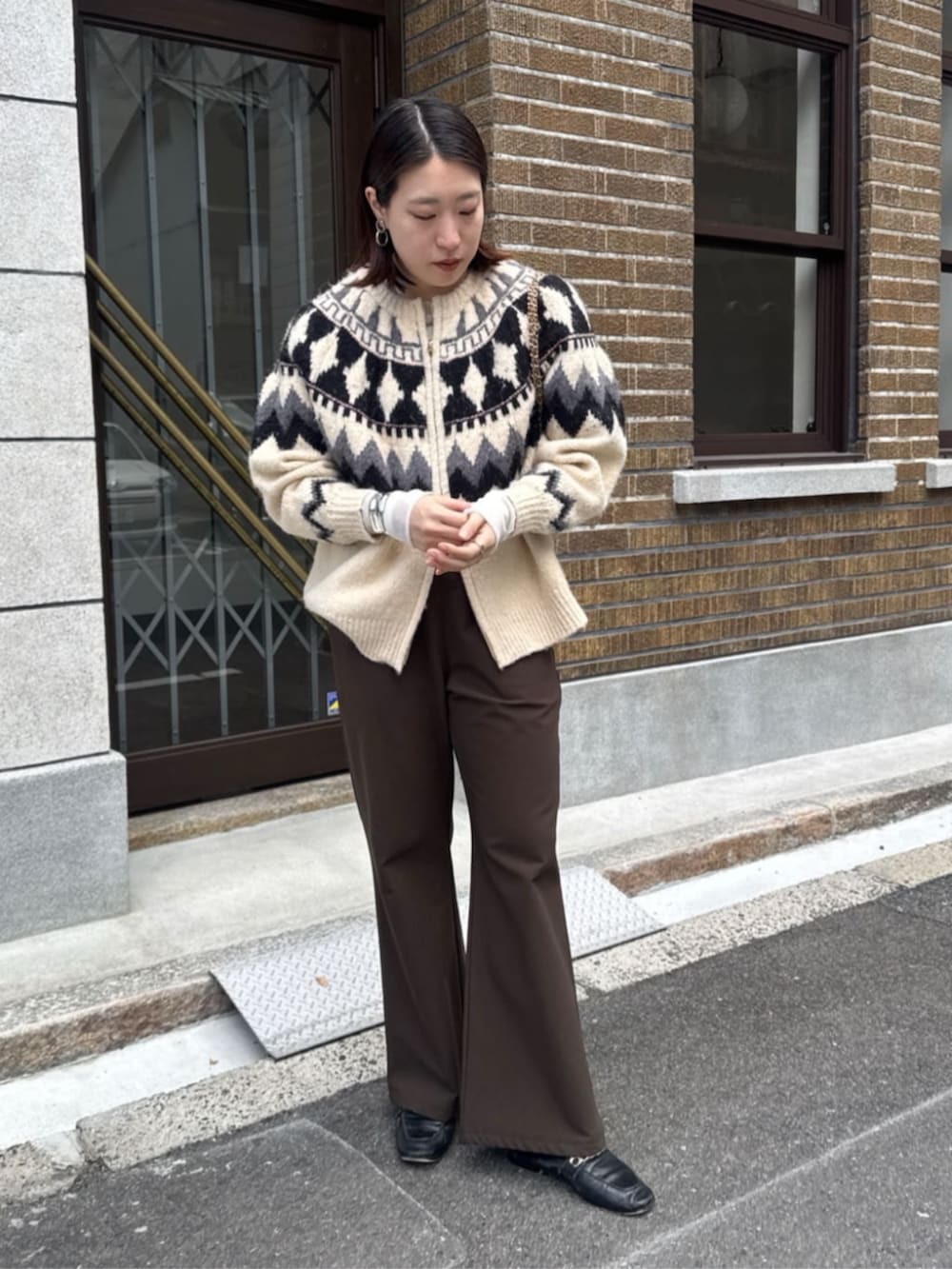 イエロー系のショルダーバッグ、ホワイト系のカーディガン/ボレロ、ブラウン系のその他パンツを着用したレディースの冬コーディネートの6枚目の写真