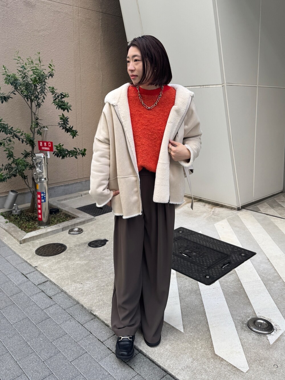 ブラウン系のスラックス、ホワイト系のその他アウター、ホワイト系のショルダーバッグを着用したレディースの秋コーディネートの4枚目の写真