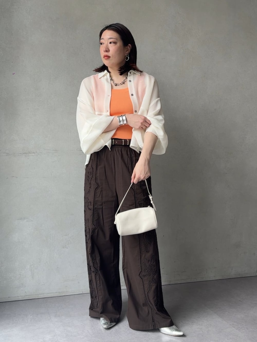 ブラウン系のその他パンツ、ホワイト系のシャツ/ブラウス、オレンジ系のニット/セーターを着用したレディースの春コーディネートの4枚目の写真