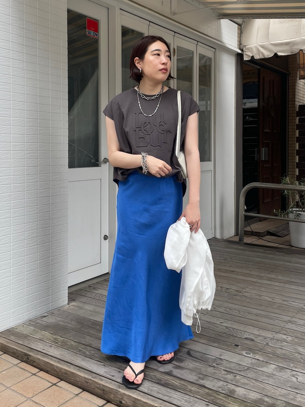 ブルー系のスカート、グレー系のTシャツ/カットソー、ホワイト系のブルゾンを着用したレディースの春コーディネートの7枚目の写真