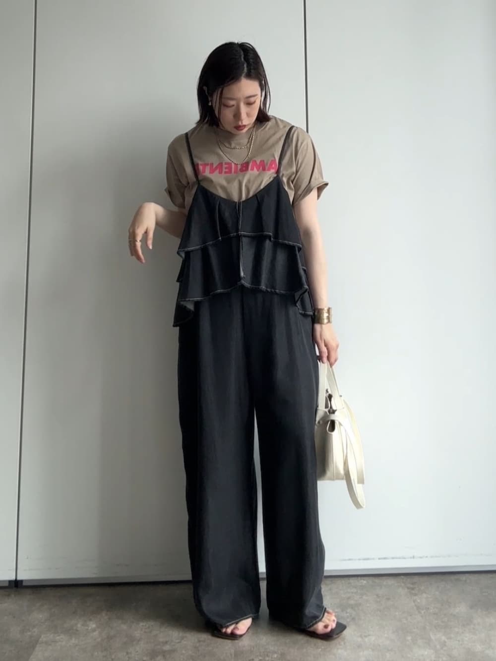 ベージュ系のテーラードジャケット、ベージュ系のTシャツ/カットソー、ブラック系のつなぎ/オールインワンを着用したレディースの夏コーディネートの2枚目の写真