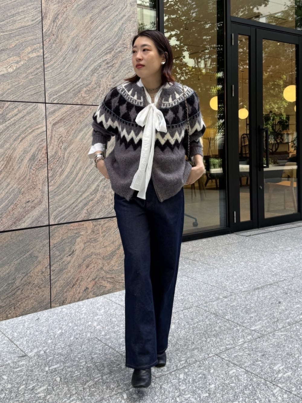 ブラック系のショルダーバッグ、ブルー系のデニムパンツ、ホワイト系のシャツ/ブラウスを着用したレディースの秋コーディネートの8枚目の写真