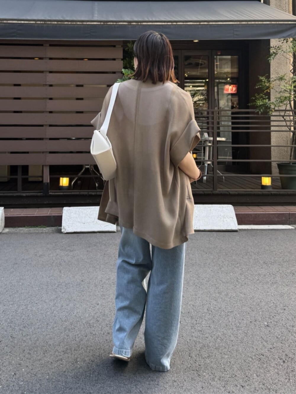 ホワイト系のショルダーバッグ、ブルー系のデニムパンツ、ブラウン系のテーラードジャケットを着用したレディースの春コーディネートの6枚目の写真