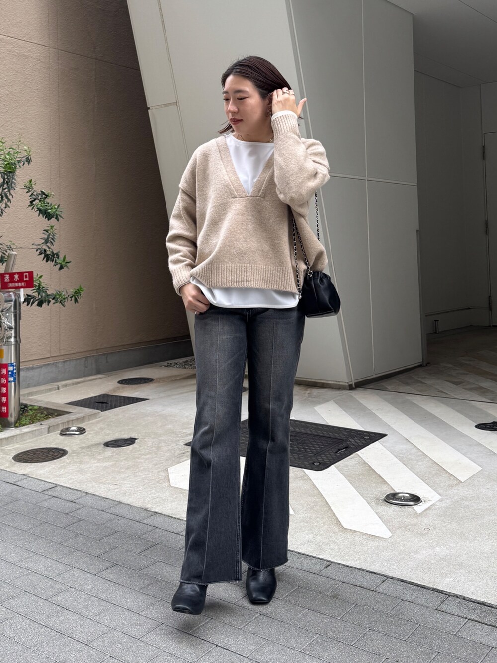 ブラック系のデニムパンツ、ベージュ系のニット/セーター、ホワイト系のTシャツ/カットソーを着用したレディースの秋コーディネートの3枚目の写真