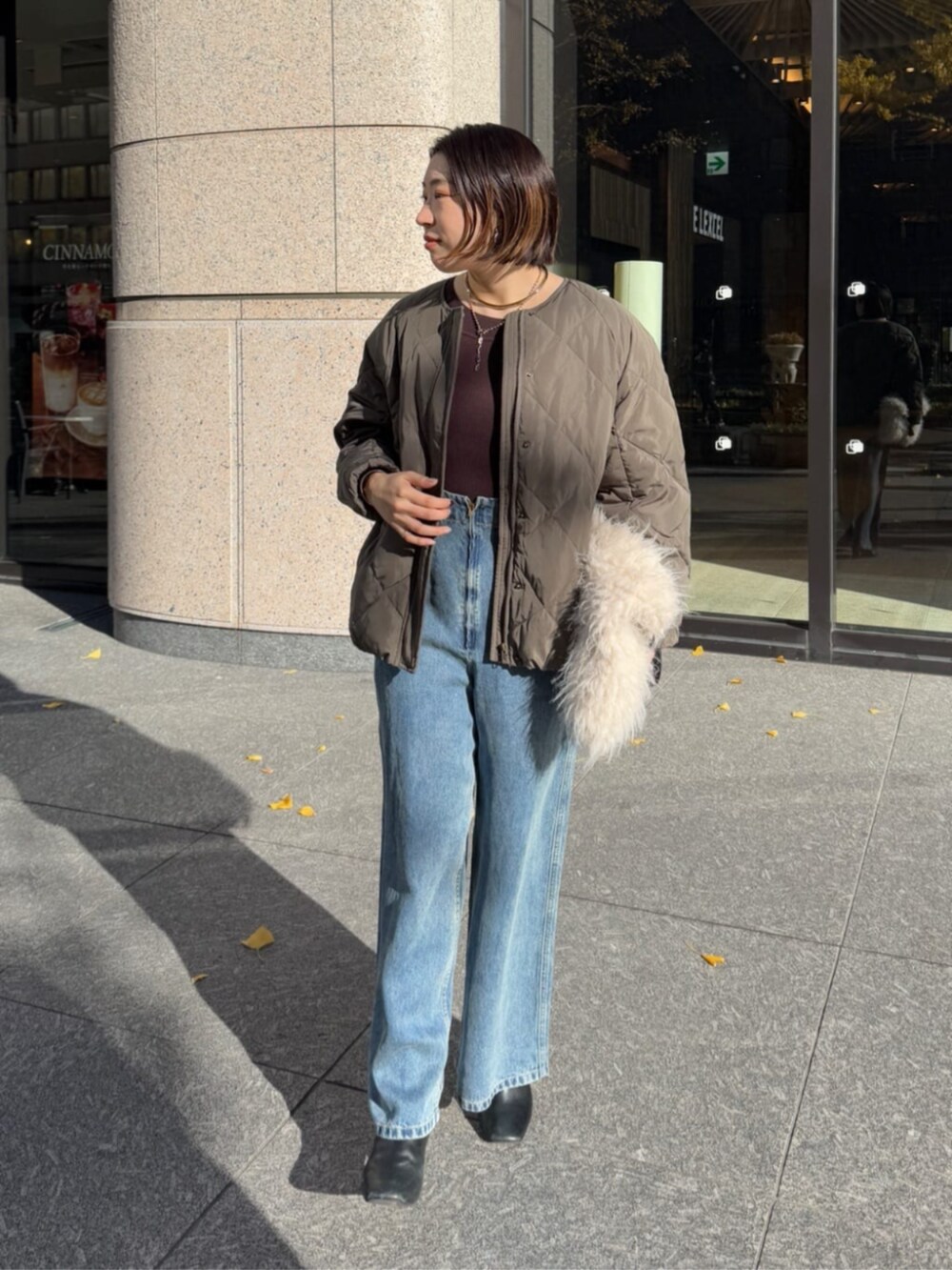 ホワイト系のショルダーバッグ、ブルー系のデニムパンツ、グレー系のその他アウターを着用したレディースの冬コーディネートの2枚目の写真