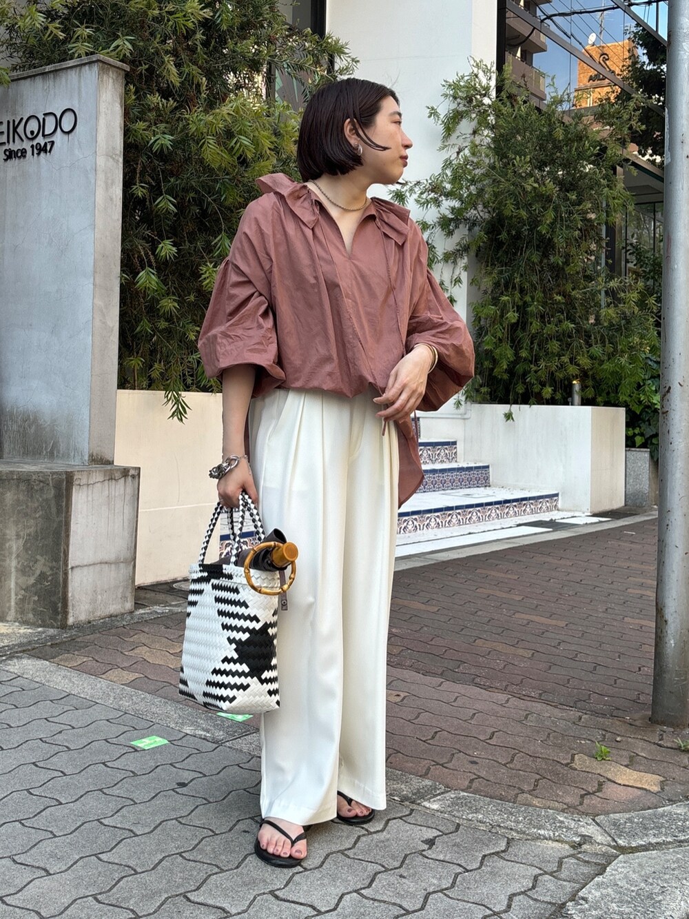 ホワイト系のスラックス、ブラウン系のシャツ/ブラウス、ホワイト系のかごバッグを着用したレディースの夏コーディネートの7枚目の写真