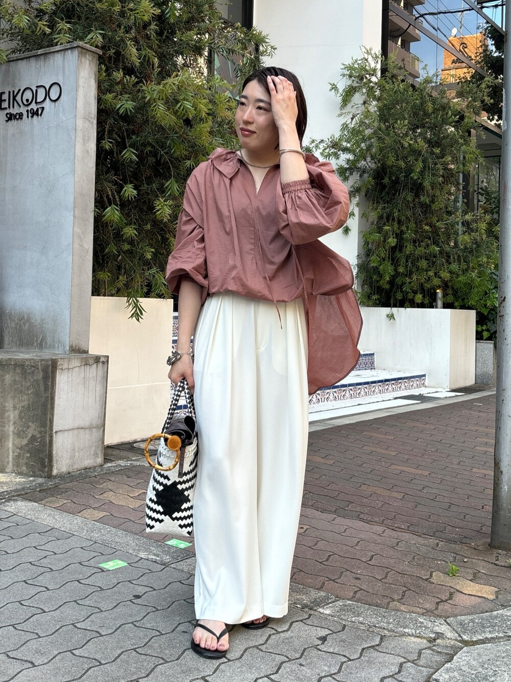 ホワイト系のスラックス、ブラウン系のシャツ/ブラウス、ホワイト系のかごバッグを着用したレディースの夏コーディネートの8枚目の写真