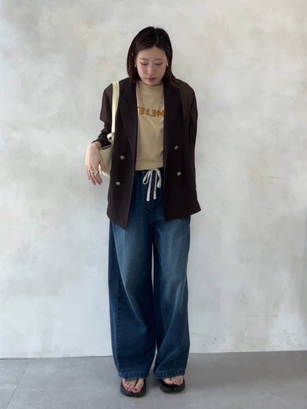 ブルー系のデニムパンツ、イエロー系のショルダーバッグ、ベージュ系のTシャツ/カットソーを着用したレディースの夏コーディネートの5枚目の写真