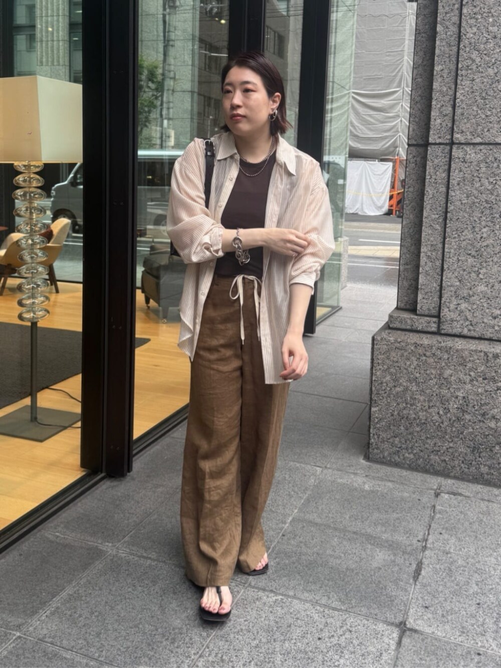 ブラウン系のショルダーバッグ、ブラウン系のTシャツ/カットソー、ベージュ系のシャツ/ブラウスを着用したレディースの夏コーディネートの4枚目の写真