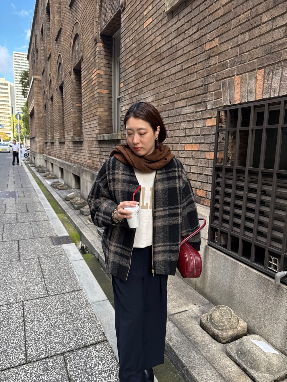 ブルー系のスラックス、ホワイト系のニット/セーター、レッド系のショルダーバッグを着用したレディースの秋コーディネートの4枚目の写真