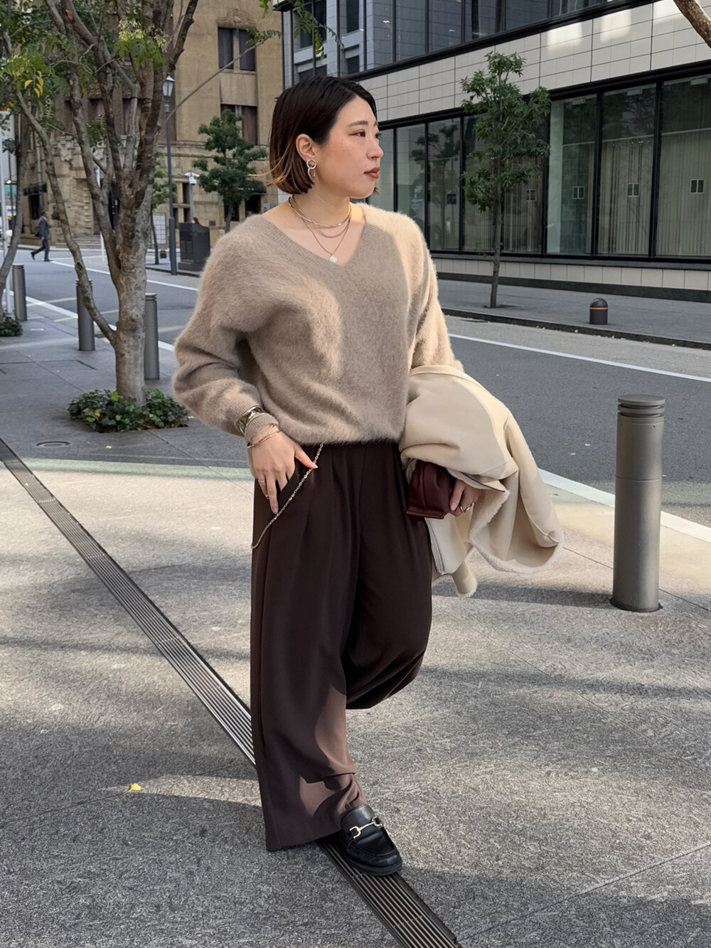 ブラウン系のスラックス、ブラウン系のニット/セーター、ホワイト系のその他アウターを着用したレディースの冬コーディネートの8枚目の写真