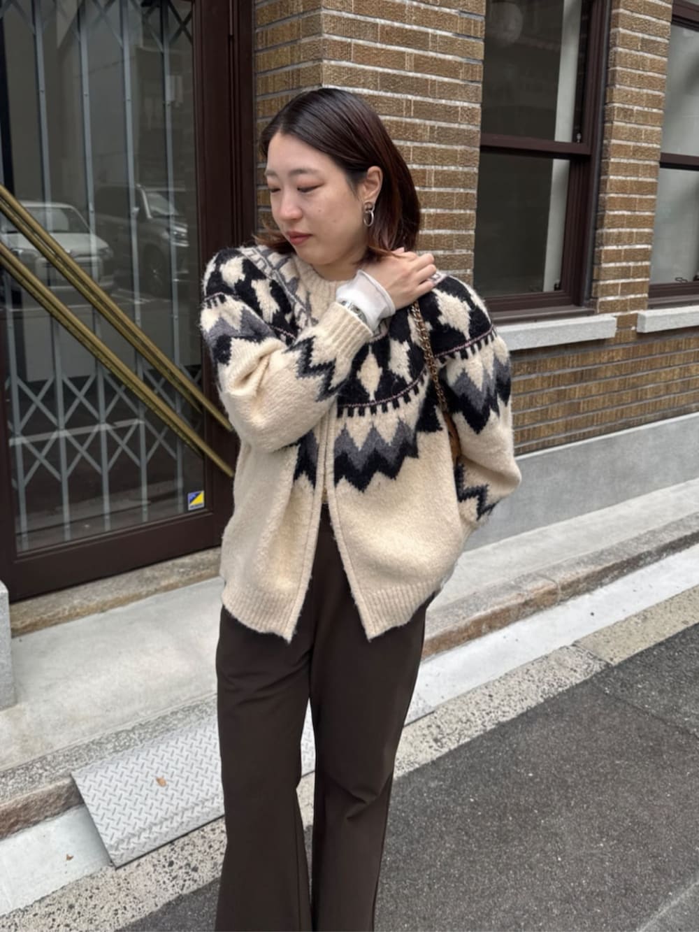 イエロー系のショルダーバッグ、ホワイト系のカーディガン/ボレロ、ブラウン系のその他パンツを着用したレディースの冬コーディネートの7枚目の写真