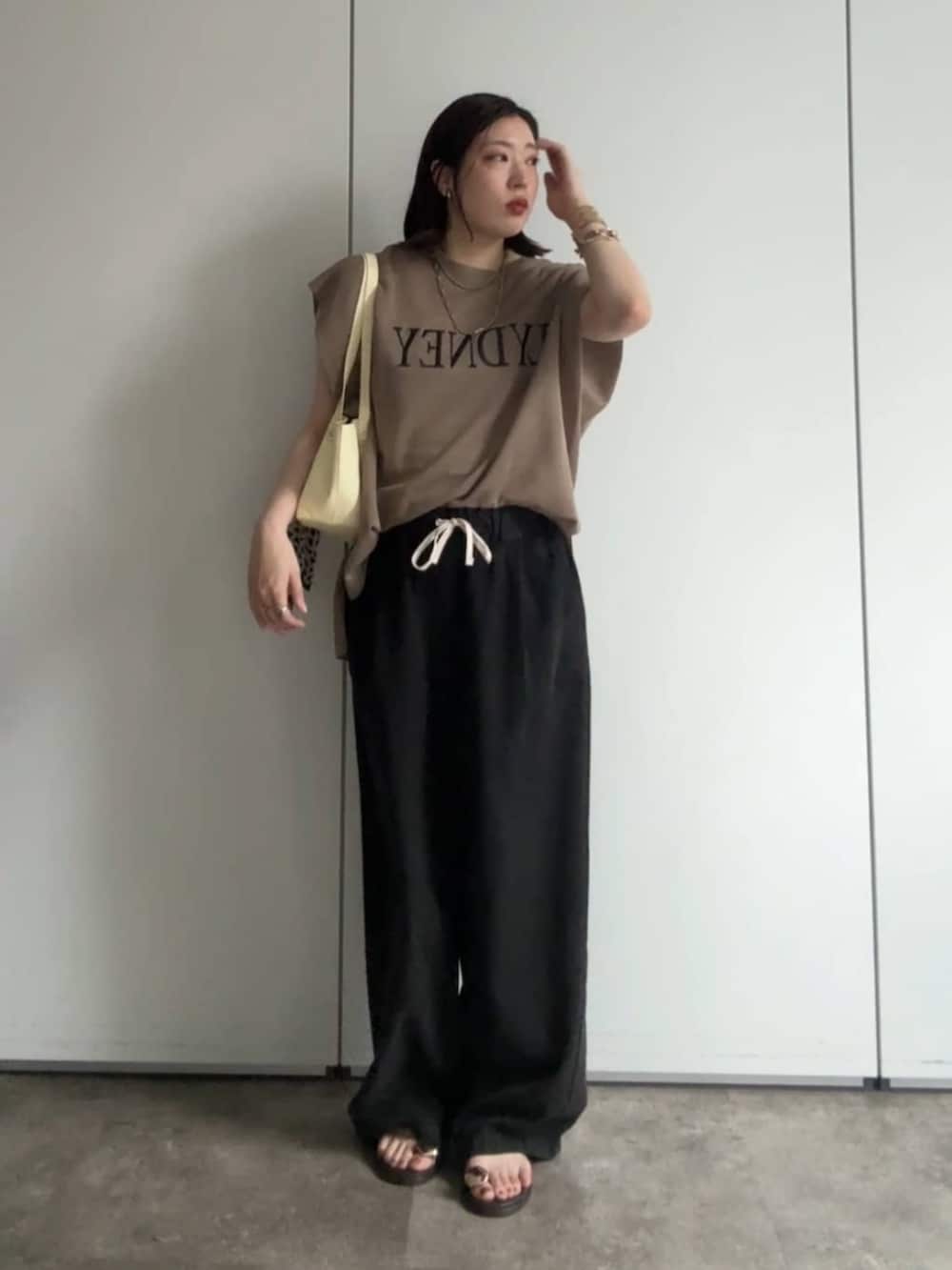 イエロー系のショルダーバッグ、ブラウン系のサンダル、ブラック系のデニムパンツを着用したレディースの夏コーディネートの2枚目の写真