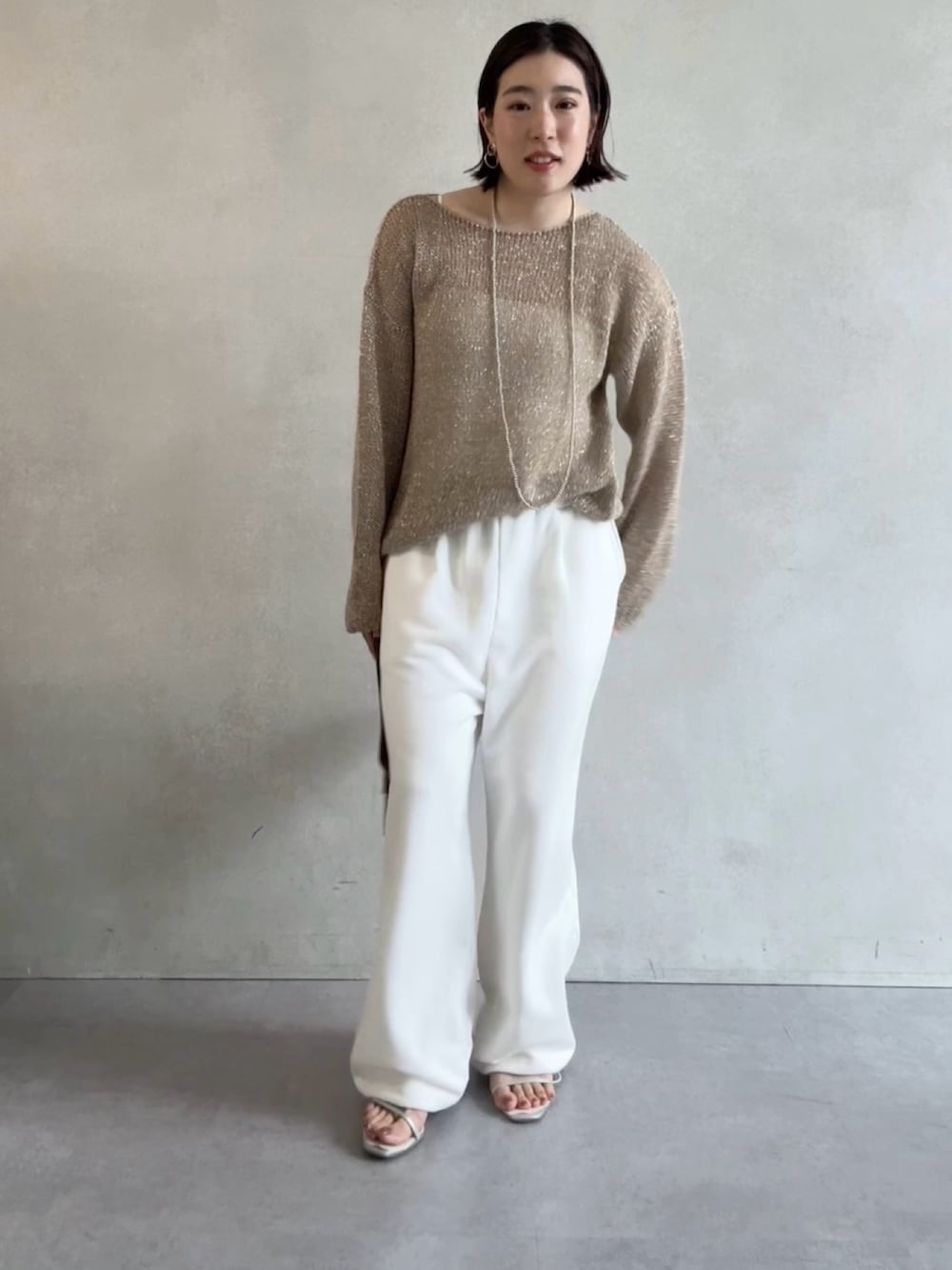 ホワイト系のスウェットパンツ、ベージュ系のニット/セーター、ブラウン系のショルダーバッグを着用したレディースの秋コーディネートの3枚目の写真