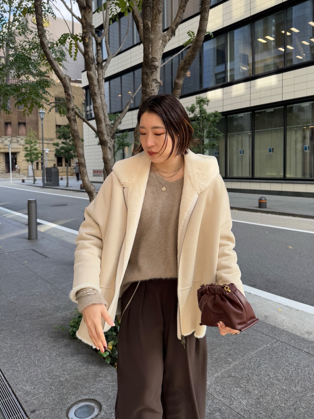 ブラウン系のスラックス、ブラウン系のニット/セーター、ホワイト系のその他アウターを着用したレディースの冬コーディネートの4枚目の写真