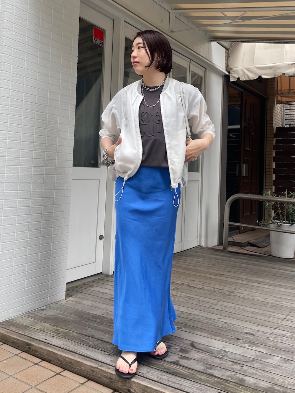 ブルー系のスカート、グレー系のTシャツ/カットソー、ホワイト系のブルゾンを着用したレディースの春コーディネートの3枚目の写真