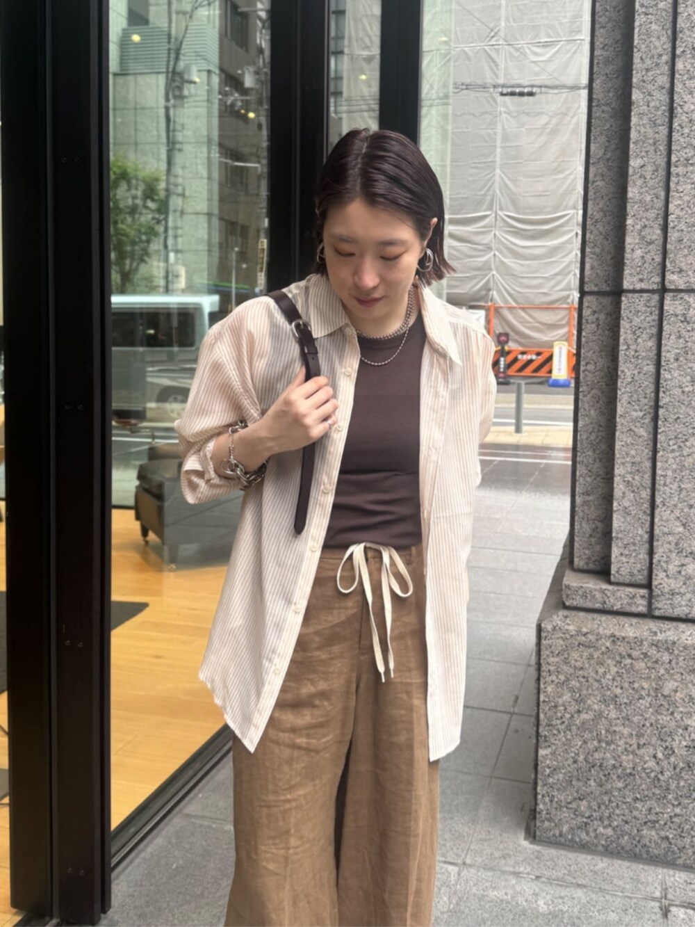 ブラウン系のショルダーバッグ、ブラウン系のTシャツ/カットソー、ベージュ系のシャツ/ブラウスを着用したレディースの夏コーディネートの7枚目の写真