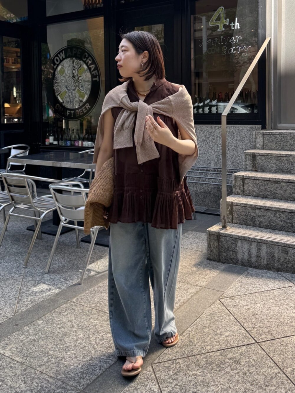 ブルー系のデニムパンツ、ベージュ系のカーディガン/ボレロ、ブラウン系のシャツ/ブラウスを着用したレディースの春コーディネートの9枚目の写真