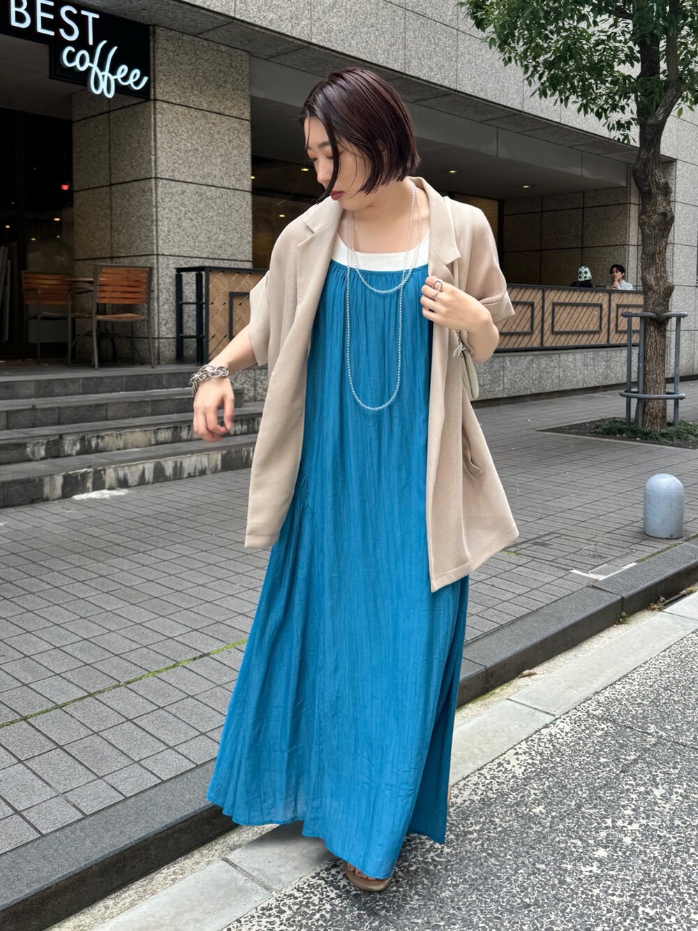 ベージュ系のテーラードジャケット、ホワイト系のタンクトップ、ブルー系のワンピースを着用したレディースの夏コーディネートの3枚目の写真