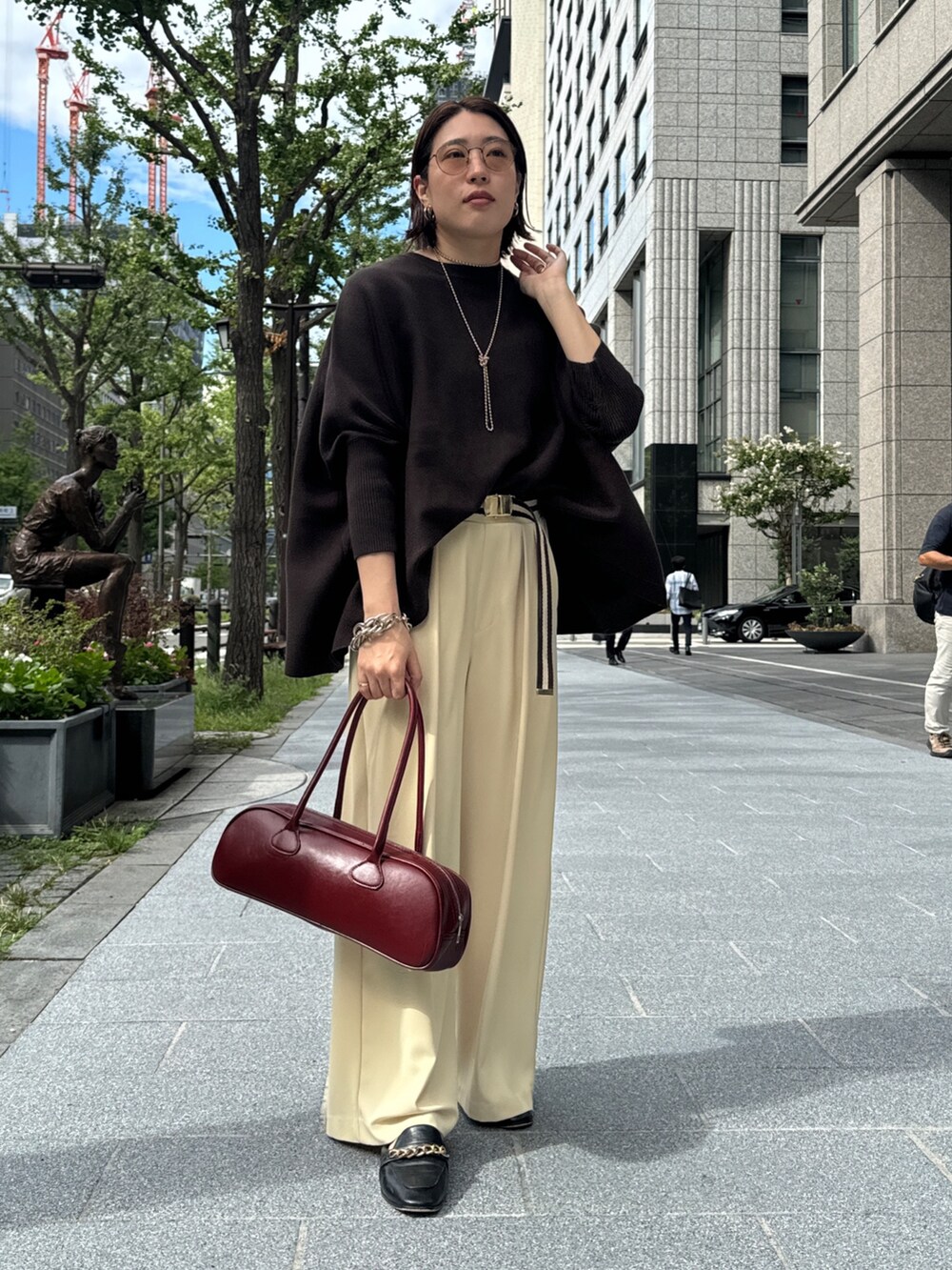 イエロー系のスラックス、ブラウン系のニット/セーター、ゴールド系のネックレスを着用したレディースの秋コーディネートの9枚目の写真