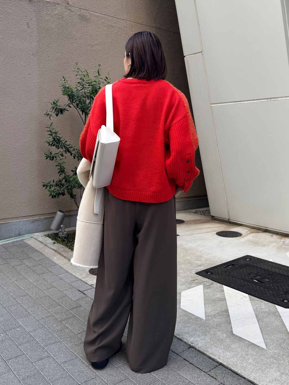 ブラウン系のスラックス、ホワイト系のその他アウター、ホワイト系のショルダーバッグを着用したレディースの秋コーディネートの6枚目の写真